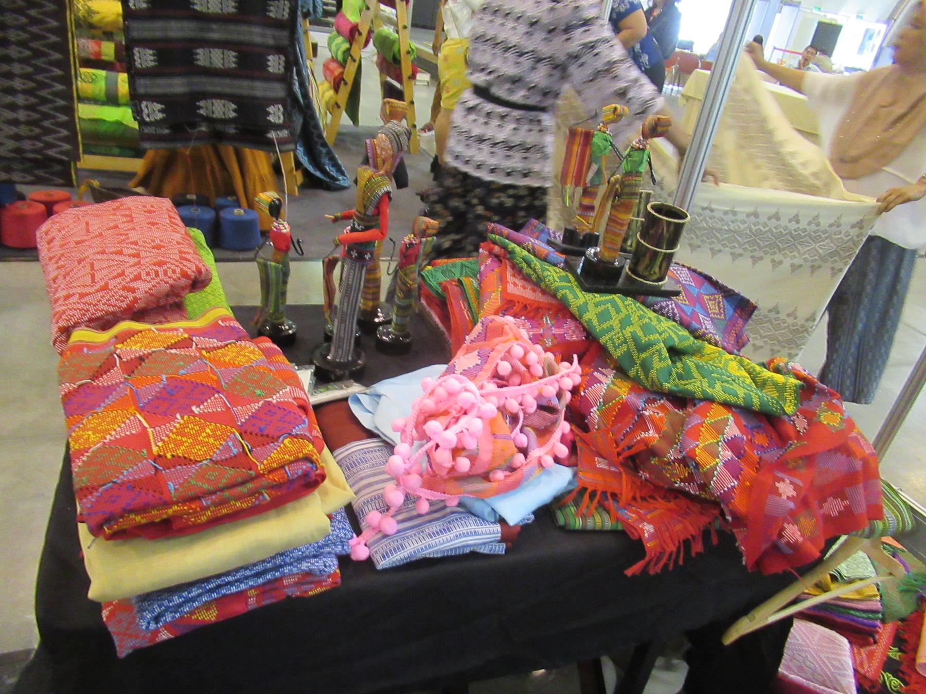'Likha' (Exhibit) 35 - a table with a bunch of colorful blankets and a stuffed elephant